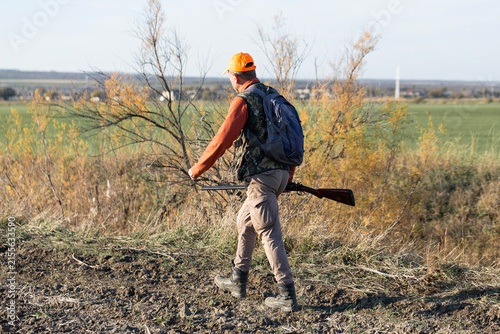 A hunter with a gun in camouflage clothing. A gentleman with a gun, medium shot, unrecognizable.