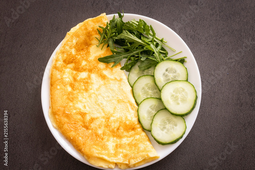 Omelette with cucumber slices and herbs on a plate