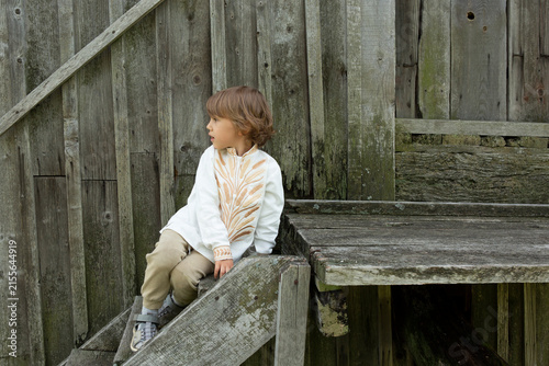 Little boy in embroidered vyshyvanka shirt sitting on a wooden staircase