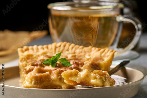 apple pie served with tea on a ceramic plate in a cozy indoor dining setting, top-down view, comforting and warm atmosphere, brown and white colors, natural light, clean background, food.