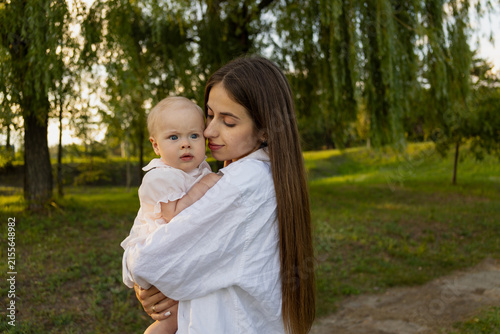 Obraz na plátně Mother tenderly holding her baby in a park during golden hour