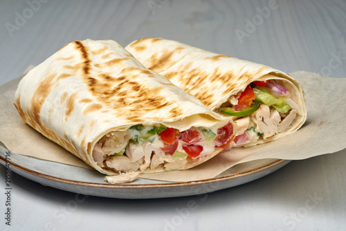 chicken wrap on a plate with parchment paper, fresh and appetizing top-down view, commercial food photography, healthy eating, white and brown colors, tortilla, chicken, vegetables.