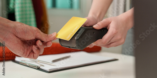Close up of customer tapping credit card on POS terminal for contactless payment