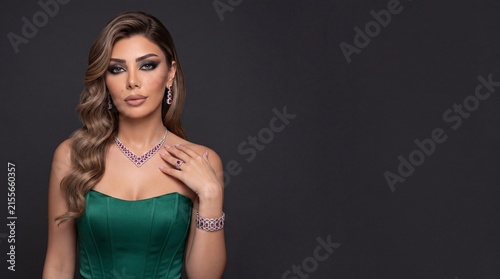 Stunning woman wearing luxury ruby red gemstone silver jewelry set in green dress, fashion model portrait with dark copy space
