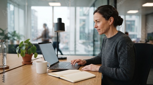 Woman working on laptop in modern office environment.