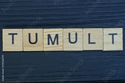 Foto text on word tumult from gray wooden letters on a black background