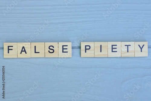 Fotografie word false piety made from wooden gray letters lies on a gray background