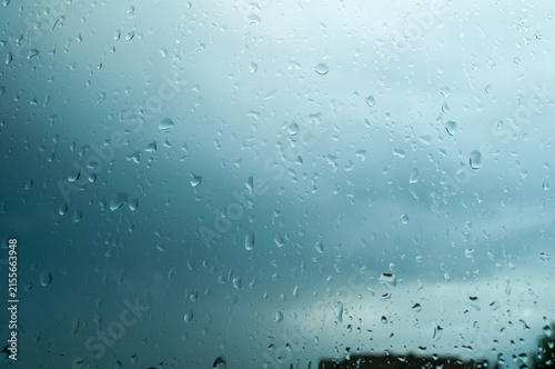 Canvas Print Water droplets clinging to window glass with a stormy overcast sky in the backgr