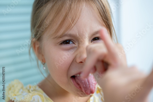 little girl making funny face sticking out tongue, playful childhood emotions, cheerful kid portrait, teasing expression, joyful expression, happy childhood moment, Adorable young child playing