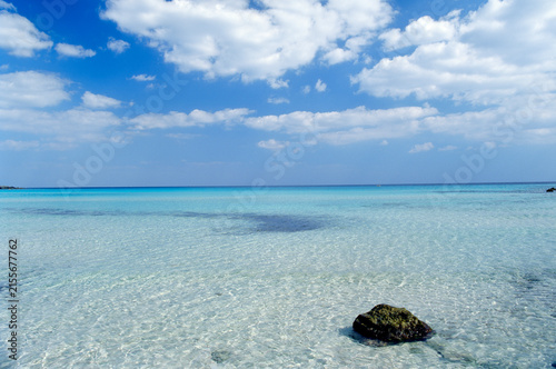 Mare cristallino turchese con roccia e cielo azzurro