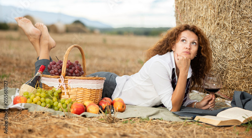 Photography Woman in white blouse spends time in field, settled down in nature with book