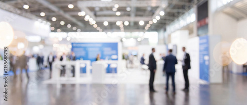 Trade show exhibition hall blurred background featuring business people networking in a bright modern convention hall, ideal for corporate event presentations and banner design