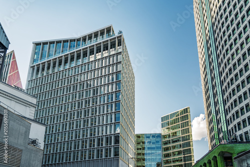 View of modern glass and steel office buildings with geometric facades under a clear blue sky in London, England, United Kingdom.