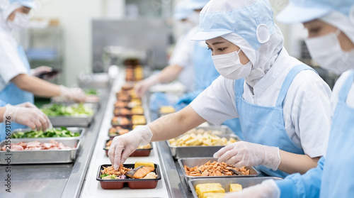 食品工場で弁当の盛り付け作業をする作業員たちの製造ライン