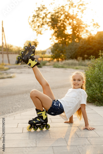 An energetic, fair-haired young woman performs tricks and stretching exercises on roller skates outdoors 