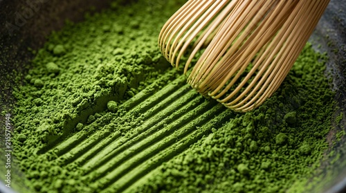 Macro shot of bamboo whisk making raked lines in green tea matcha powder inside dark bowl