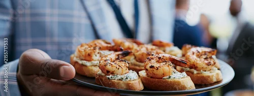 Obraz  z motywem guest holding a plate of gourmet shrimp crostini appetizers at a corporate networking buffet, 