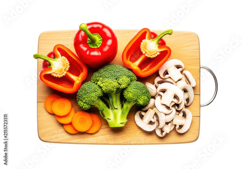 Fresh vegetables including bell peppers broccoli mushrooms and carrots arranged on a wooden cutting board for healthy cooking.