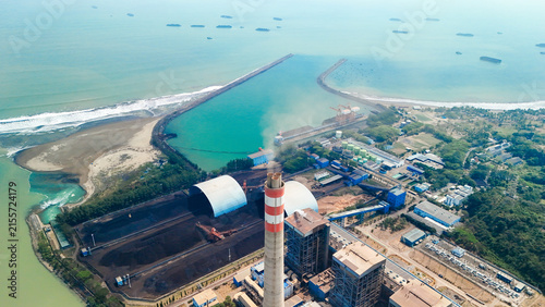 Canvas Print Aerial panorama of a power generation facility near the coastline, with smokestack emissions, industrial structures, coal piles, and energy systems