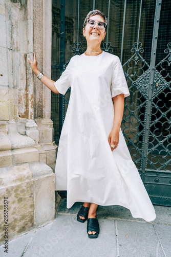 Foto Woman in white dress stands confidently outside a decorative wrought iron gate,