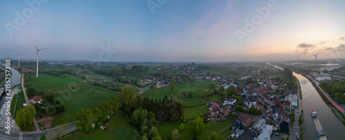 Lot, Beersel, Vlaams-Brabant, 22nd of April, 2025, Stunning aerial panorama showcasing a tranquil landscape with lush fields and winding river at sunrise.