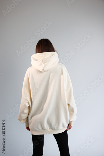 Back view of a female model wearing a blank off-white hoodie mockup.