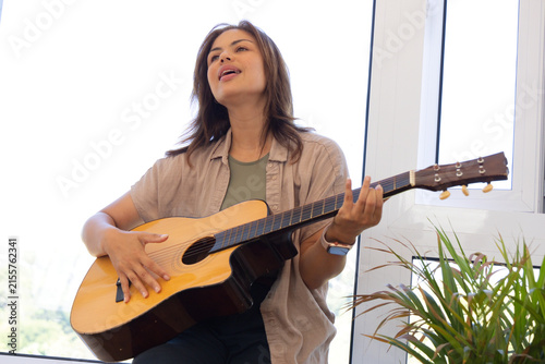 Foto African American woman sitting near windows in studio playing acoustic guitar we