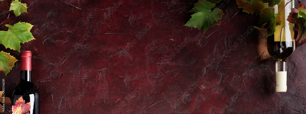 Naklejka premium Red Wine Bottles and Glass with Grapevine on Rustic Background