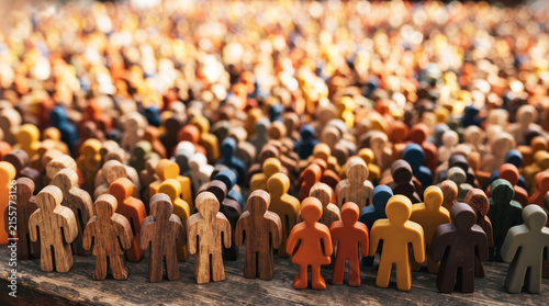 Large crowd of diverse miniature human figures standing together, representing population, community, and demographics.
