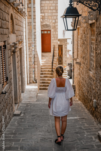 Woman walking through a narrow historic stone street in a traditional European old town
