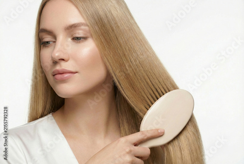 Poised Woman Adjusting Her Smooth Blonde Hairstyle With Subtle Makeup Glow