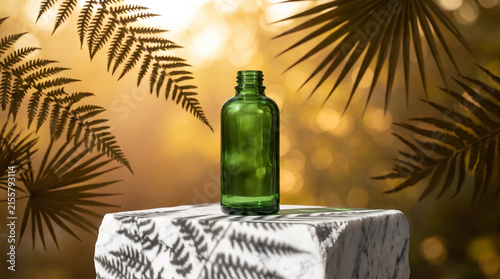 Green glass bottle on marble with leaf shadow