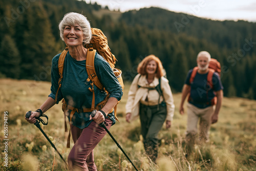 Senior hiker mountain joyful smiling, with others along and onward
