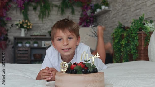 Cute preschool boy with birthday cake with candles at home, preparing for party with friends and siblings