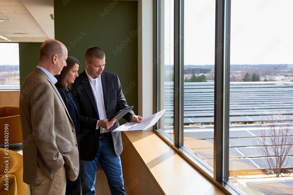 Fototapeta premium Facility managers reviewing commercial building energy costs and planning efficiency upgrades to reduce operating expenses and carbon emissions