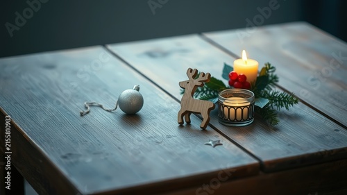 A wooden table with a festive touch, featuring a wooden reindeer figurine, a lit candle, a silver ornament, and a sprig of greenery, creating a cozy atmosphere.