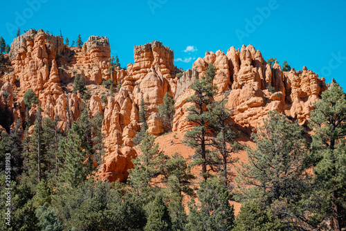 Fotografie Vivid Sunrise Illuminates Rugged Hoodoos Amidst Lush Coniferous Surroundings And