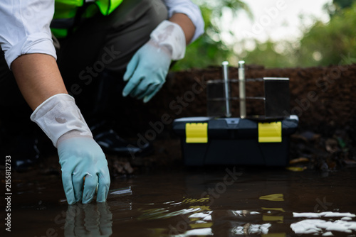 Environmental engineer collecting water quality assessment for detecting toxic chemical contamination in an irrigation canal.