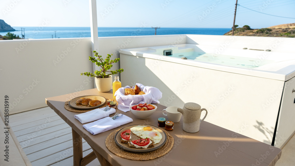 Fototapeta premium Delightful breakfast on a balcony overlooking the serene coast of Milos, Greece