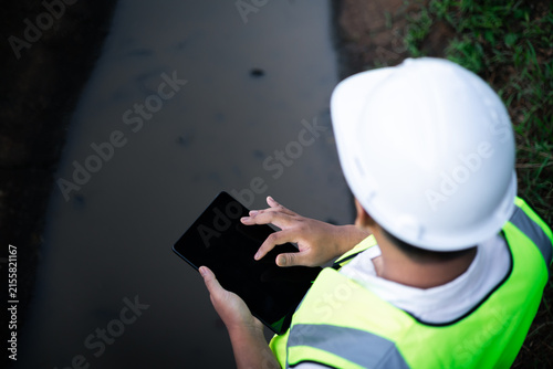 Bild auf Leinwand Environmental engineer testing water quality in irrigation canal using field equipment and tablet