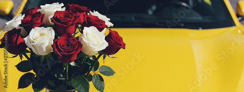 Mazzo di rose rosse e rose bianche sul cofano di una automobile di colore giallo - regali e ricorrenze