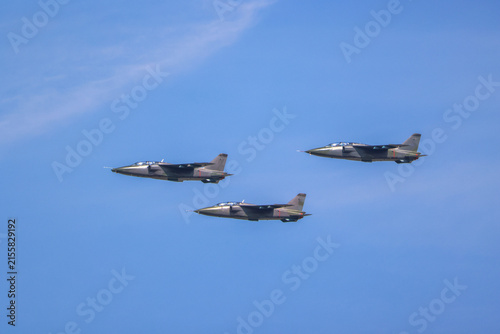 Three military fighter jets flying in a coordinated formation across a clear blue sky, showcasing power, precision, and defense aviation capabilities during an air show display.
