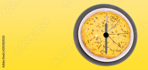 Lancette d'orologio sovrapposte a piatti con frittata, su uno sfondo giallo - ora di pranzo