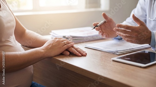 Pregnant woman and doctor discussing prenatal care during a medical consultation in a clinic office