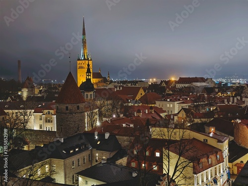 High angle view of Tallinn Old Town skyline at night, illuminated spire of St Olaf Church and medieval towers.