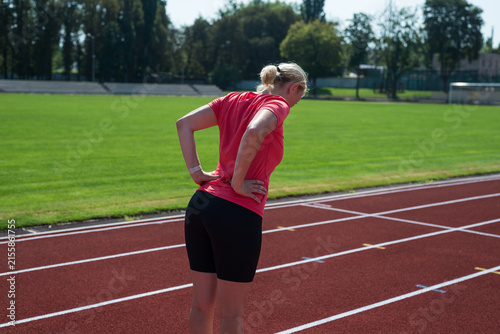 Tired sportswomen feel back and hip pain while doing sports, health care concept.