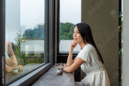 Принти на полотні Woman sitting by large window looking outside thoughtfully