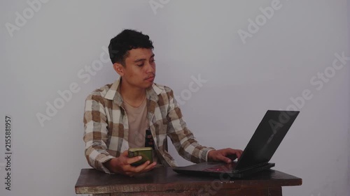 Focused Young Man Engaging with Technology: A Portrait of Modern Work and Communication in a Minimalist Setting