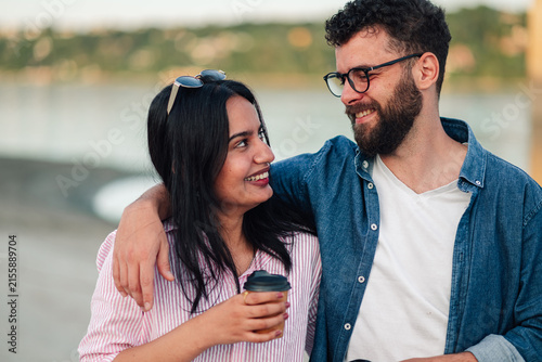 Canvas Print Smiling mixed race couple enjoying outdoor coffee break, embracing happiness and