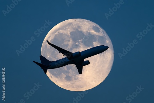 Passenger airplane flying in front of large detailed full moon silhouette of jetliner taking off against lunar surface background